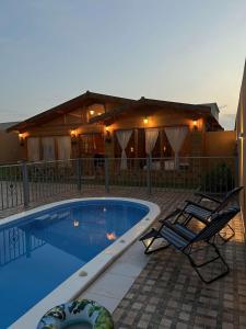 einen Pool mit zwei Stühlen und ein Haus in der Unterkunft شاليةالخفجي in Al Khafji