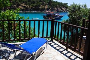 a blue chair on a balcony with a boat in the water at Aliki Stone House in Alyki