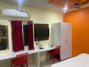 a room with a desk with a computer and two red chairs at HOTEL SPACE SETTER in Bhubaneshwar
