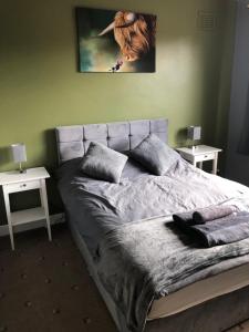 1 dormitorio con 1 cama con 2 mesas y una foto en la pared en 2 Bedroom Bungalow, en Mawdesley