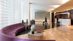 two people sitting on a purple couch in a lobby at Courtyard by Marriott Shin-Osaka Station in Osaka