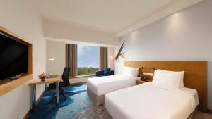 a hotel room with two beds and a desk and a tv at Novotel Hyderabad Convention Centre in Hyderabad