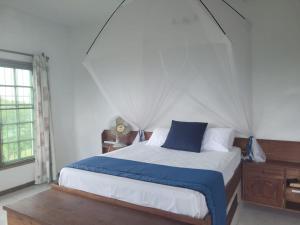 a bedroom with a bed with a blue pillow and a window at Sea and sun in Cidade de Nacala
