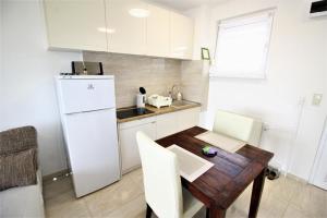 eine Küche mit einem Holztisch und einem weißen Kühlschrank in der Unterkunft Rest House Apartman in Nyíregyháza
