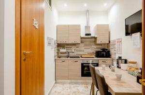 uma cozinha com uma mesa com cadeiras e um lavatório em Mi casa tu casa - Guest House em Catânia