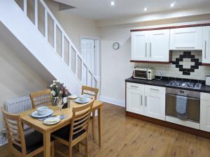 cocina y comedor con mesa y sillas en White Cottage, en Llandudno