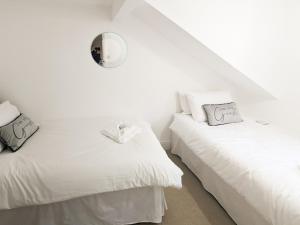 dos camas blancas sentadas una al lado de la otra en una habitación en White Cottage, en Llandudno