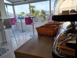 a room with chairs and a bar with a window at Cit'Hotel Les Atlantes in Médis