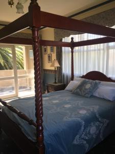 um quarto com uma cama de dossel e um edredão azul em Toorak Manor Hotel em Melbourne