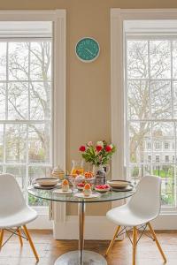 een eetkamer met een tafel en stoelen en een klok bij Stylish Grade II Listed Apartment: The London in Cheltenham