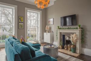 a living room with a blue couch and a fireplace at Stylish Grade II Listed Apartment: The London in Cheltenham