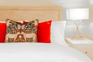 een wit bed met rode kussens en een lamp bij Stylish Grade II Listed Apartment: The London in Cheltenham