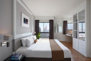 a bedroom with a white bed and a large window at Somerset Park Suanplu Bangkok in Bangkok
