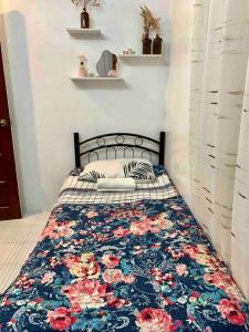 um quarto com uma cama com um cobertor floral em Cozy House with Peaceful Vibes em Dinalupihan