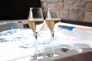 2 copas de vino blanco junto a una bañera de hidromasaje en Villa Wood - Gîte de prestige en Ardennes - 10 personnes - Sauna, jacuzzi, piscine et billard, en Tenneville