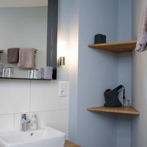 a white bathroom with a sink and shelves at Villa Westend in Norderney