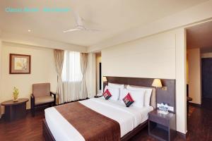 a hotel room with a large bed and a chair at Whispering Palms Hotel Jaipur in Jaipur