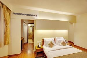 a hotel room with a bed with white sheets and pillows at Whispering Palms Hotel Jaipur in Jaipur