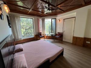 een slaapkamer met een bed in een kamer met ramen bij Little Heaven in Nainital