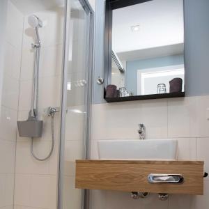 a bathroom with a sink and a shower with a mirror at Villa Westend in Norderney
