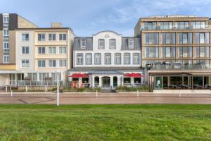 a group of buildings on a street with grass at Strandvilla an der Kaiserwiese in Norderney