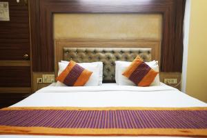 een slaapkamer met een groot bed met oranje en paarse kussens bij Hotel Classic in New Delhi
