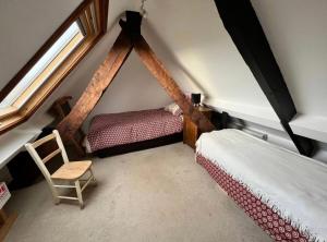 a attic bedroom with two beds and a chair at Sleepy Hollow in Taunton