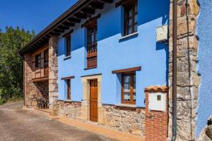 un edificio azul con puertas y ventanas de madera en Apartamento Rural Celada 2, 