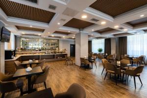 a restaurant with tables and chairs and a bar at Renion Residence Hotel in Almaty