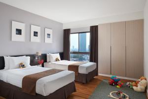 a hotel room with two beds and a window at Somerset Park Suanplu Bangkok in Bangkok