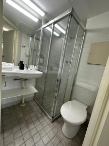 a bathroom with a shower and a toilet and a sink at DCH on Mitchell in Darwin
