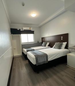 1 dormitorio con 2 camas y ventana en DCH on Mitchell, en Darwin