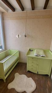Pokój z 2 łóżeczkami dziecięcymi, stołem i biurkiem w obiekcie Gite de la Fontaine w mieście La Bazouge-des-Alleux
