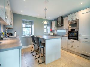 a kitchen with white cabinets and a island with chairs at Speed The Plough- Uk43631 in Grange