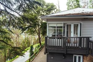 uma pequena casa com um alpendre com uma varanda em Luxury Treetop Escape with a Garden glasshouse em Kalorama