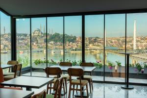 a restaurant with tables and chairs and a view of a city at Csk The Halich Port İstanbul in Istanbul