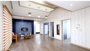 Una habitación grande con suelos de madera y paredes azules. en Jeju Olle House, en Jeju