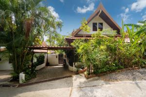 a house with a gate and palm trees at Thai Style 2BR Villa in Nai Harn Beach