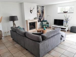 sala de estar con sofá gris y chimenea en Beach Villa Makkum, en Makkum