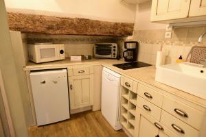 een keuken met witte kasten, een wastafel en een magnetron bij Truffle in Sarlat-la-Canéda