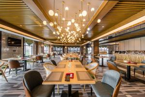 a restaurant with tables and chairs and a chandelier at Hilmanhomeful Hotel - Caijia Subway Station in Chongqing