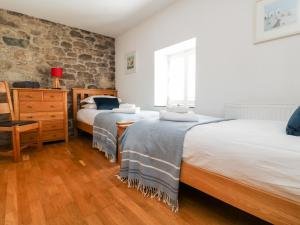two beds in a bedroom with a stone wall at Black Rock in St Austell