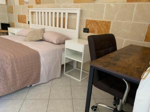 een slaapkamer met een bed, een bureau en een stoel bij Apt Riviera degli Haethey in Otranto