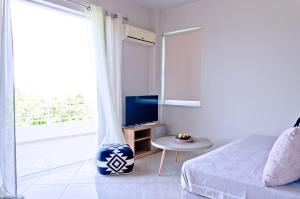 a bedroom with a bed and a television and a table at Barbaras Apartments in Kato Daratso