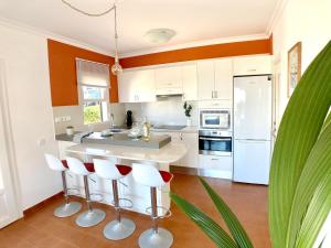 a kitchen with white cabinets and red accents at La Casa del Jardin. Menorca in Punta Grossa