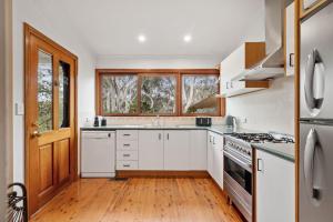 cocina con electrodomésticos blancos y suelo de madera en Scribbly Gum, en Leura