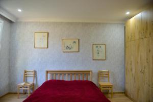 a bedroom with a red bed and two chairs at Surami Guest House - სახლი სურამში in Surami