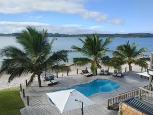 un complejo con piscina, palmeras y agua en Mukumbura Lodge Bilene en Vila Praia Do Bilene