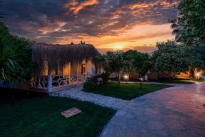 ein Haus mit einem Grasdach mit einem Sonnenuntergang im Hintergrund in der Unterkunft Naturelife Bungalows & SPA in Cıralı