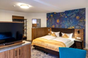 a bedroom with a bed with a television and a painting at Trip Inn City Hotel Giessen in Gießen
